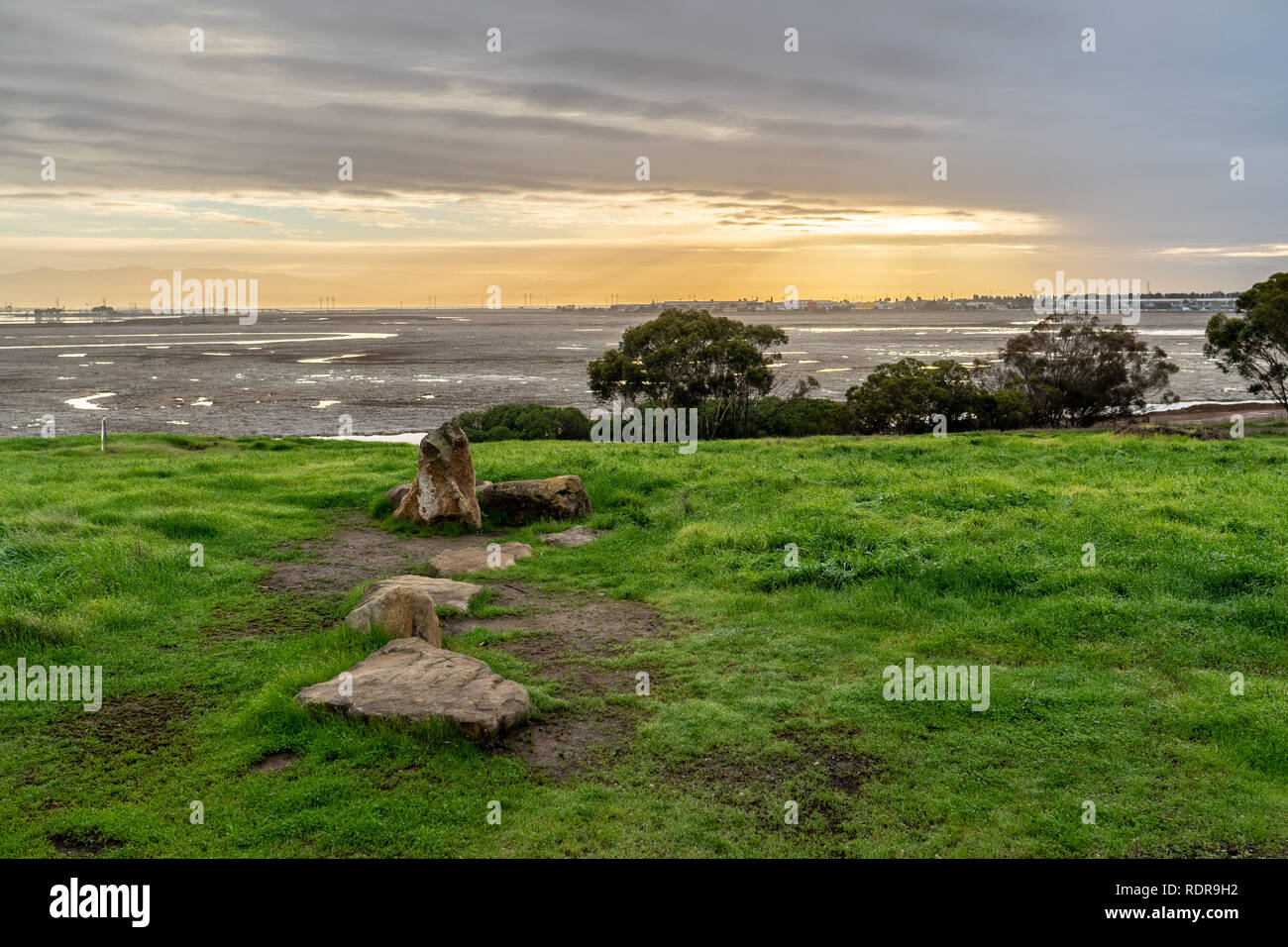 Felsen und Gras auf einem hügeligen Gelände mit der Dimensionierung von Sun spähen durch die Wolken, Bedwell Bayfront Park, Menlo Park, Kalifornien Stockfoto