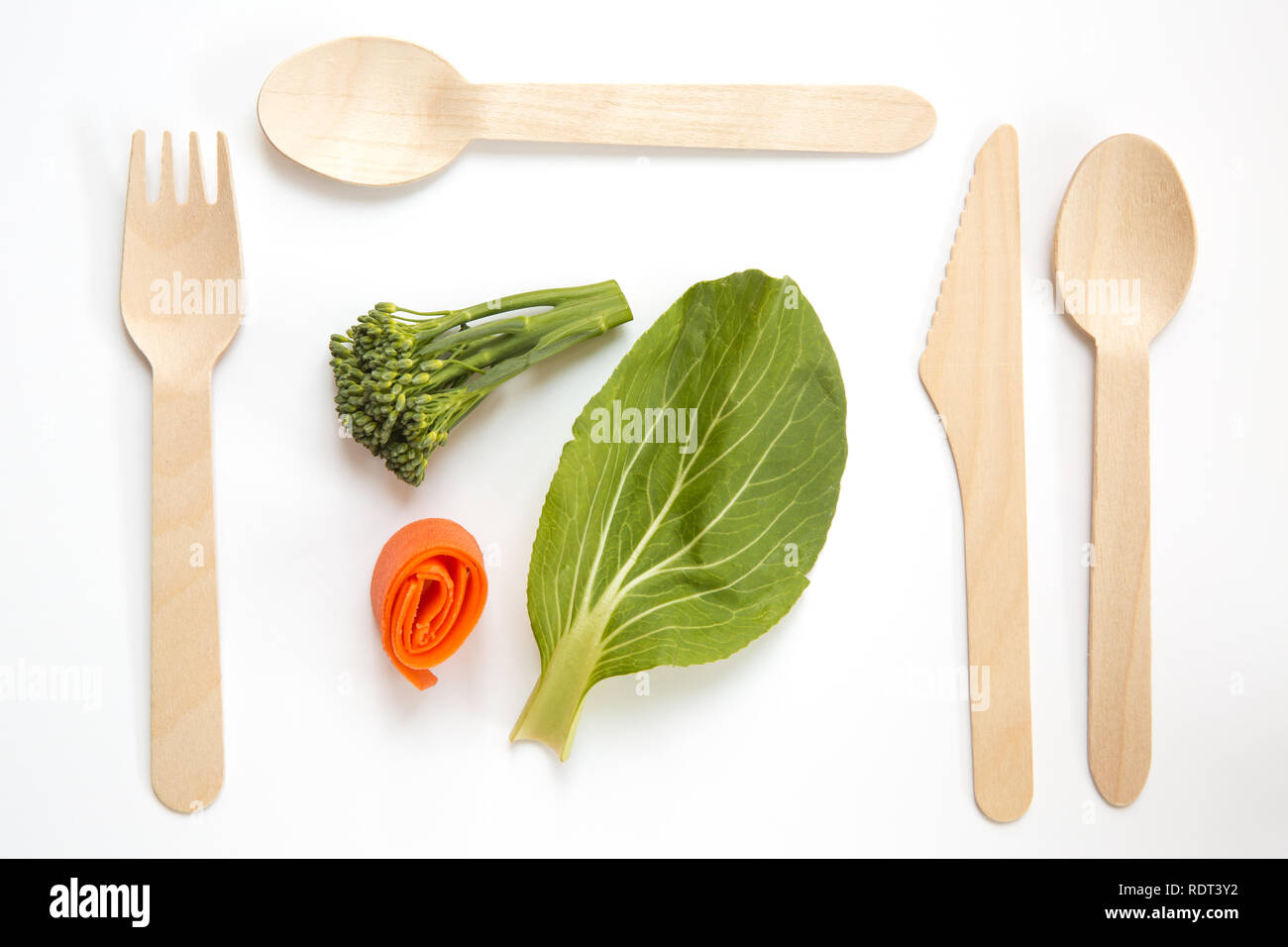 Ein Flach von frischem Blattgemüse und vegane oder vegetarische Kost mit umweltfreundlichen und Wegwerf Besteck aus Holz in einem Ort, Einstellung Stockfoto