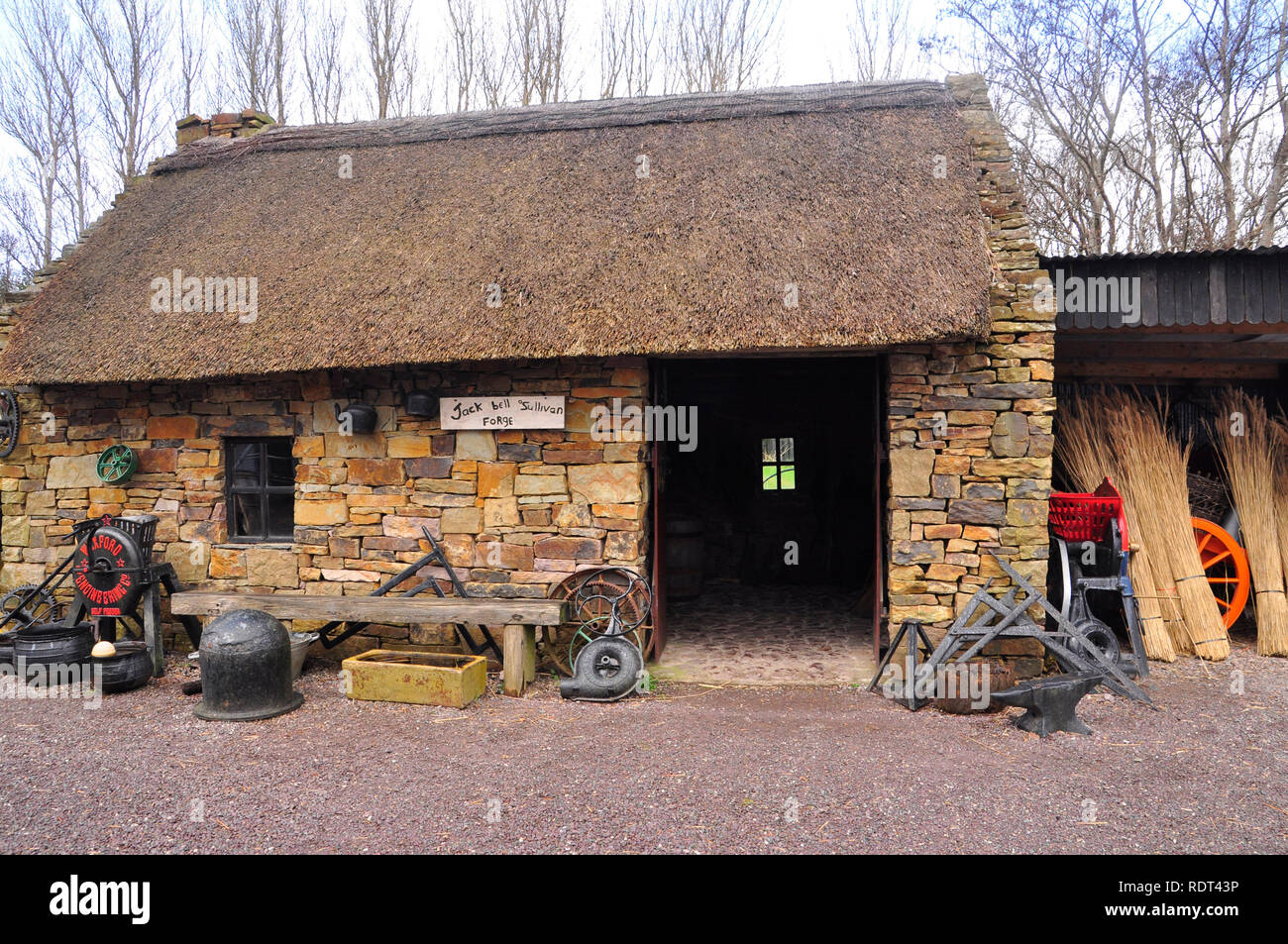 Die Kerry Bog Dorf-schmiede, mit Strohdach und alte Werkzeuge, Arbeitsgeräte und eisernen Töpfen draußen. County Kerry, Republik Irland. Stockfoto