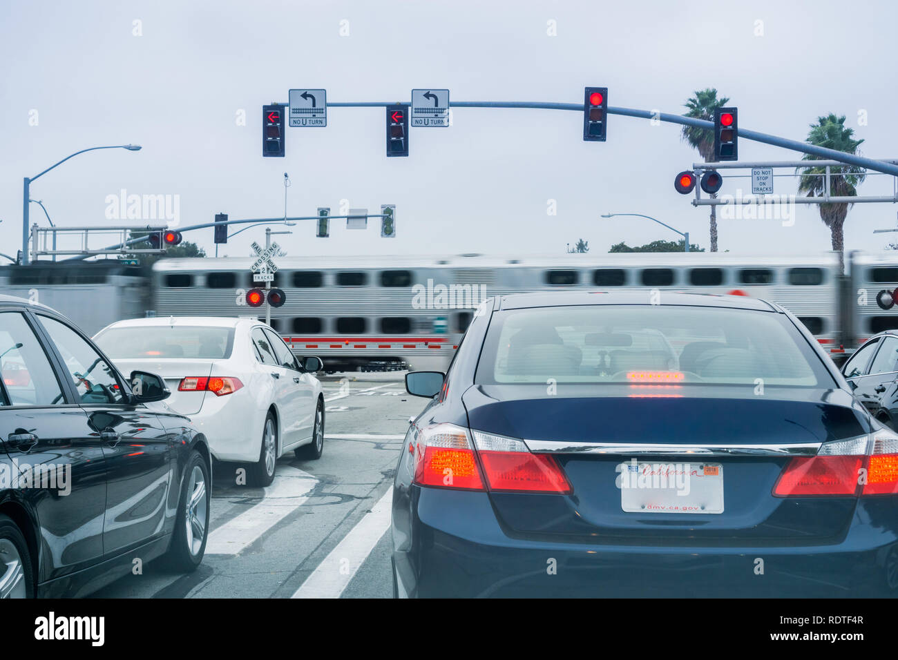 Januar 17, Sunnyvale 2018/CA/USA - Fahrzeuge warten an einer roten Ampel; high speed Zug passiert im Hintergrund, San Francisco Bay Area, C Stockfoto