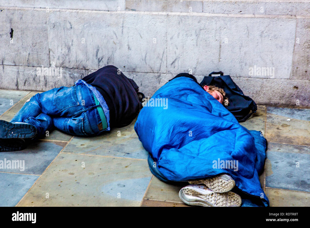 London, Großbritannien. Zwei Männer schlafen auf den Straßen der Hauptstadt - eine in einen Schlafsack und eine ohne. Stockfoto