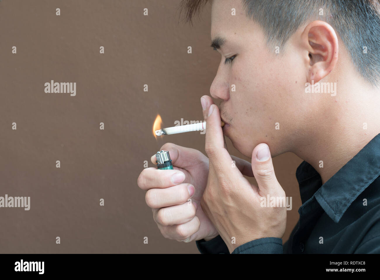 Seitenansicht des jungen Mannes ist Rauchen gegen braunen Hintergrund. Stockfoto