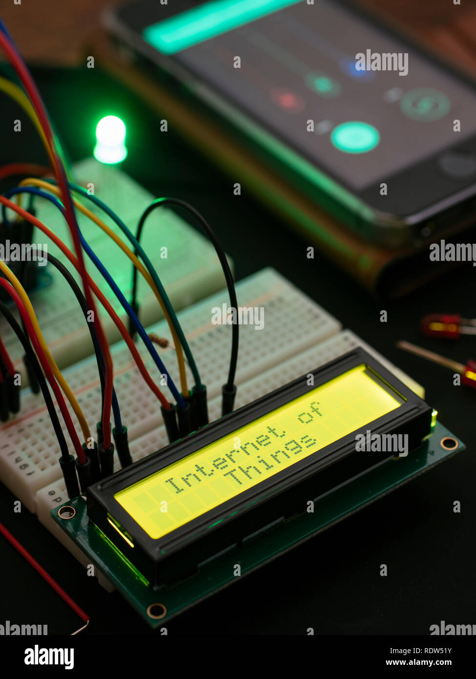 LCD-Anzeige auf einem Mikrocontroller, der den Text "Internet der Dinge" verbunden, die von einem Mobiltelefon ausgelöst. Stockfoto