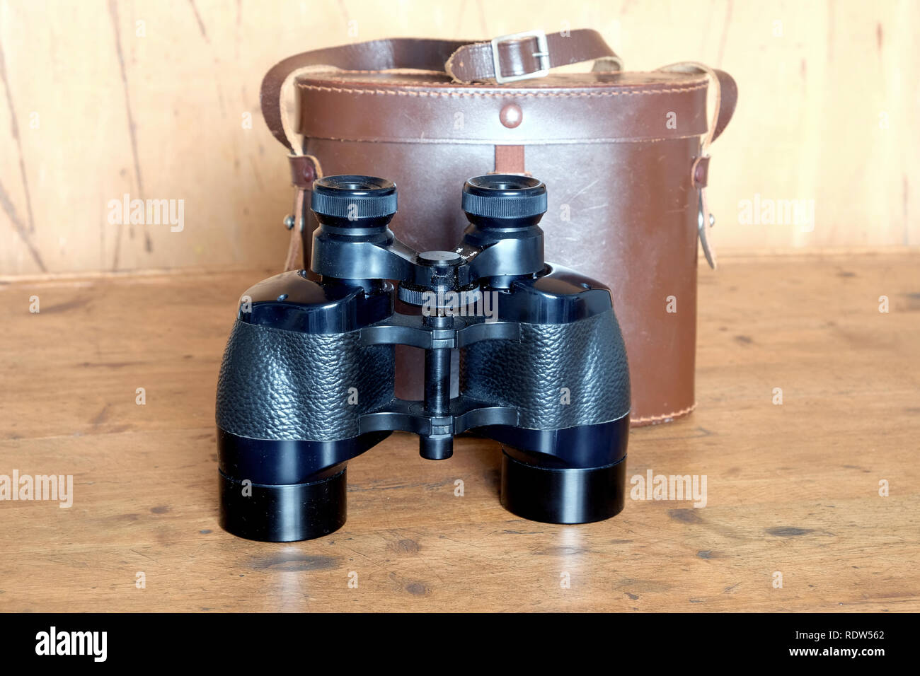 Vintage Dachkant Fernglas schwarz und braun Leder-bereitschaftstasche auf hölzernen Hintergrund Vorderansicht indoor closeup Stockfoto