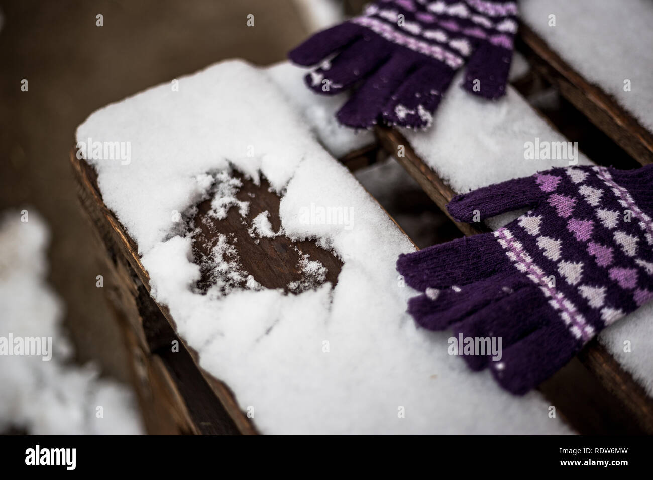 Herzen im Schnee auf einer Holzbank und Winter Handschuhe gezeichnet. Valentinstag Hintergrund Konzept. Stockfoto