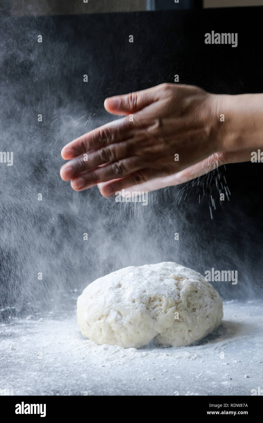 Der Teig mit Mehl durch femae Hände Stockfoto