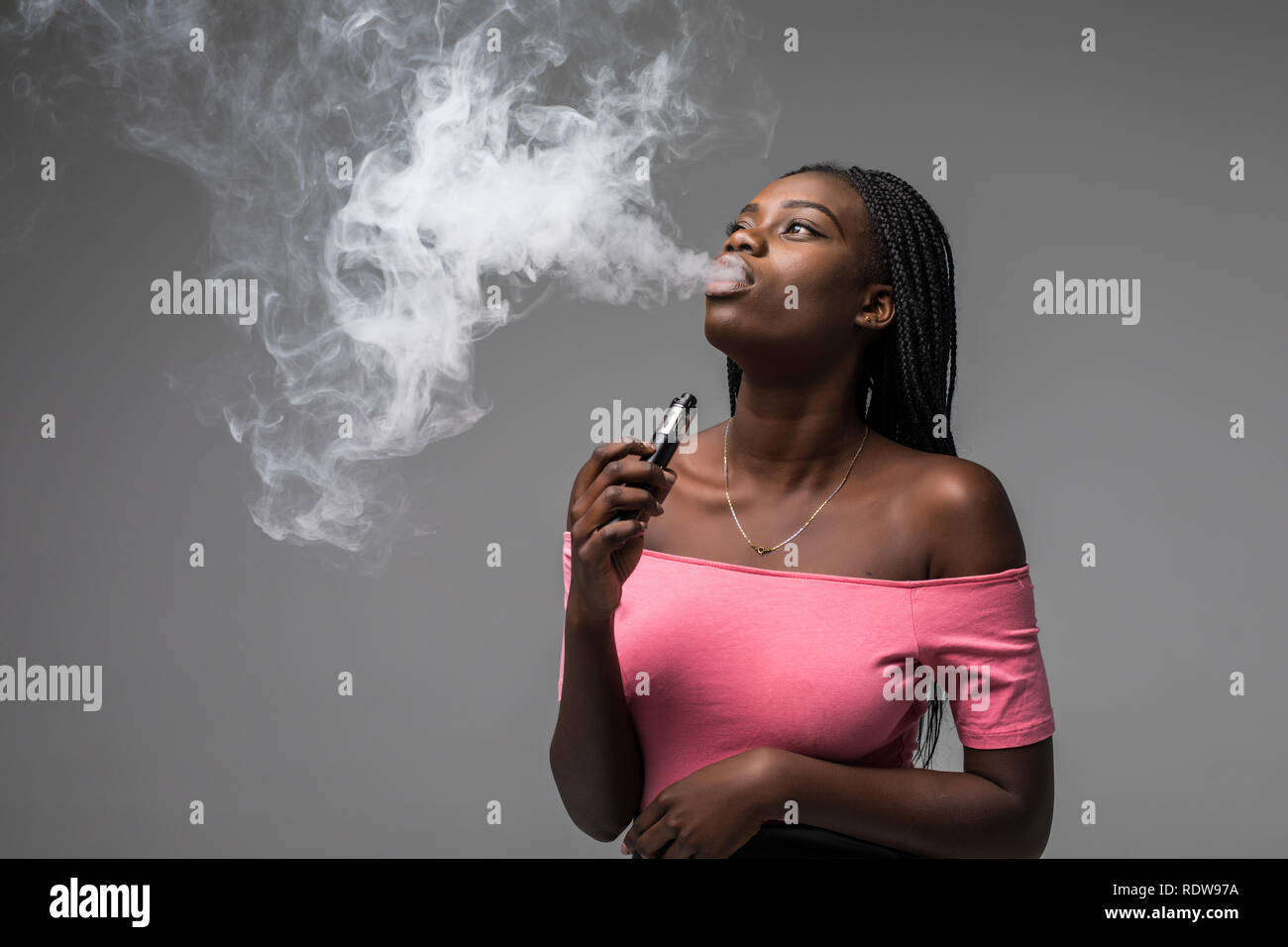 Junge Schönheit afrikanische Frau Rauch vape, e-Zigarette, auf grauem  Hintergrund Stockfotografie
