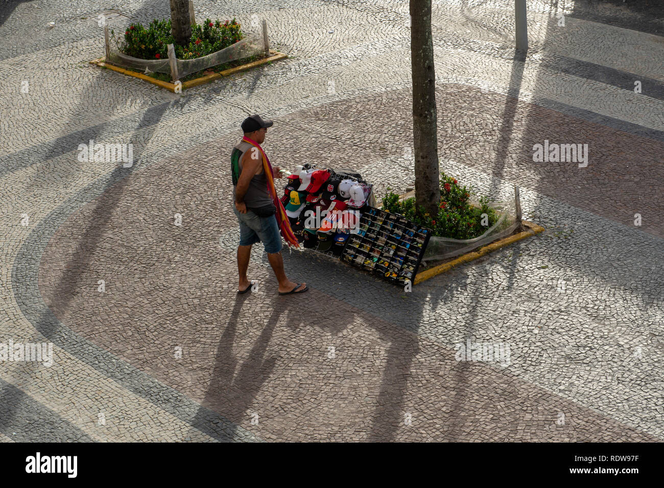RIO DE JANEIRO, RJ, Brasilien - 27. Dezember 2018: einem Straßenhändler steht vor seiner Produkte zum Verkauf an der Copacabana Bürgersteig auf ein Sommer Stockfoto
