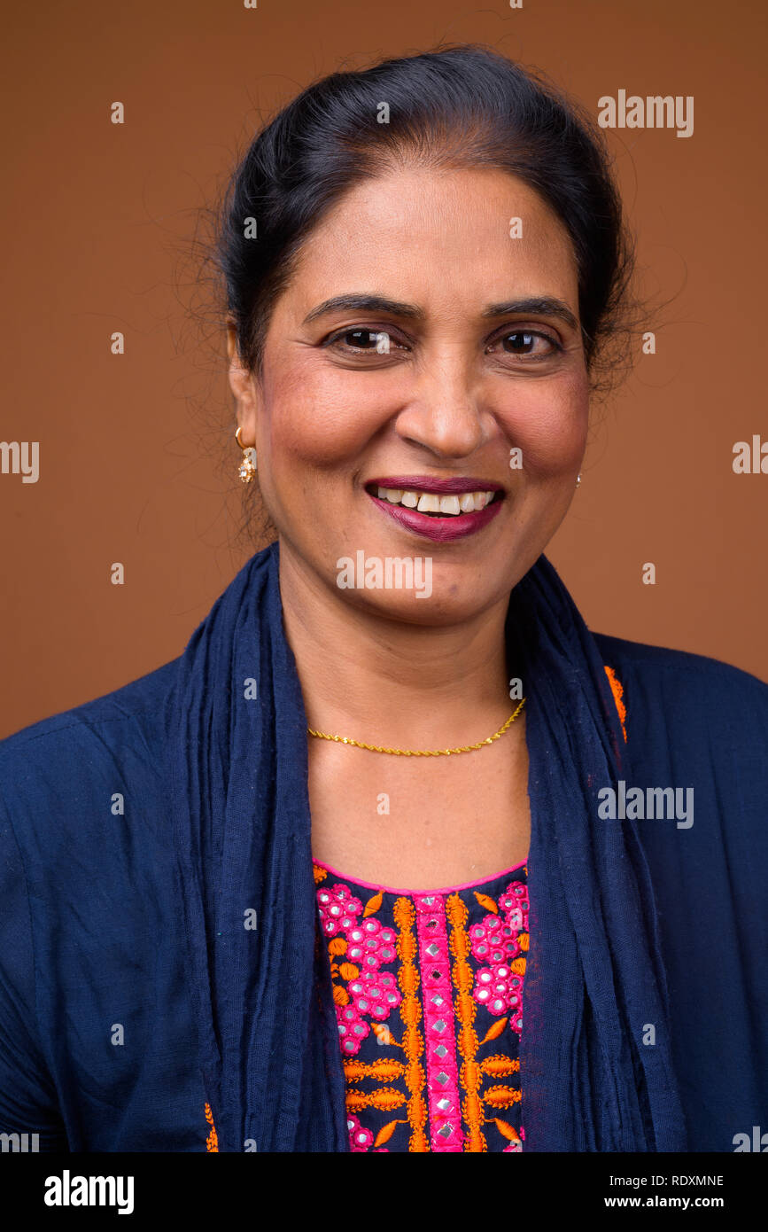 Angesichts der schönen indischen Frau gegen braunen Hintergrund lächelnd Stockfoto