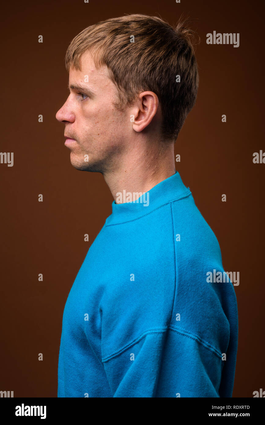 Mann mit blauen Pullover gegen braunen Hintergrund Stockfoto