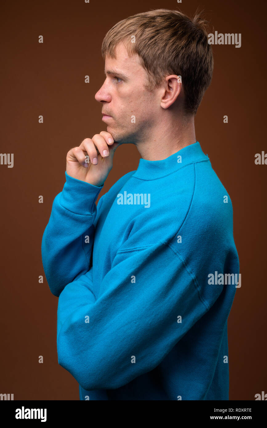 Mann mit blauen Pullover gegen braunen Hintergrund Stockfoto