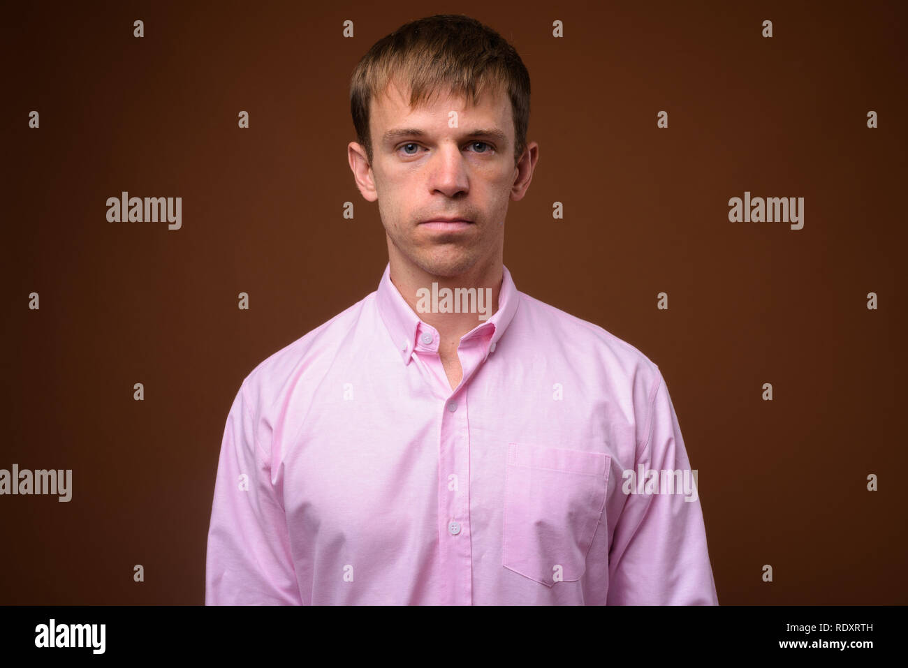 Unternehmer tragen rosa Shirt gegen braunen Hintergrund Stockfoto