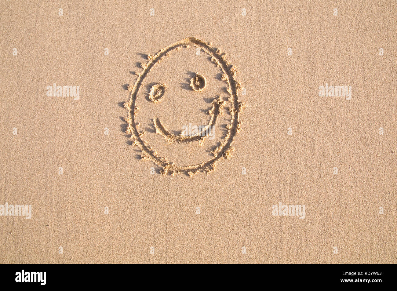Ein Symbol oder eine Grafik glückliches Gesicht auf einer sauberen Strand Sand gezeichnet. Eine Grafik für Sommer Urlaub oder Freizeit. Stockfoto