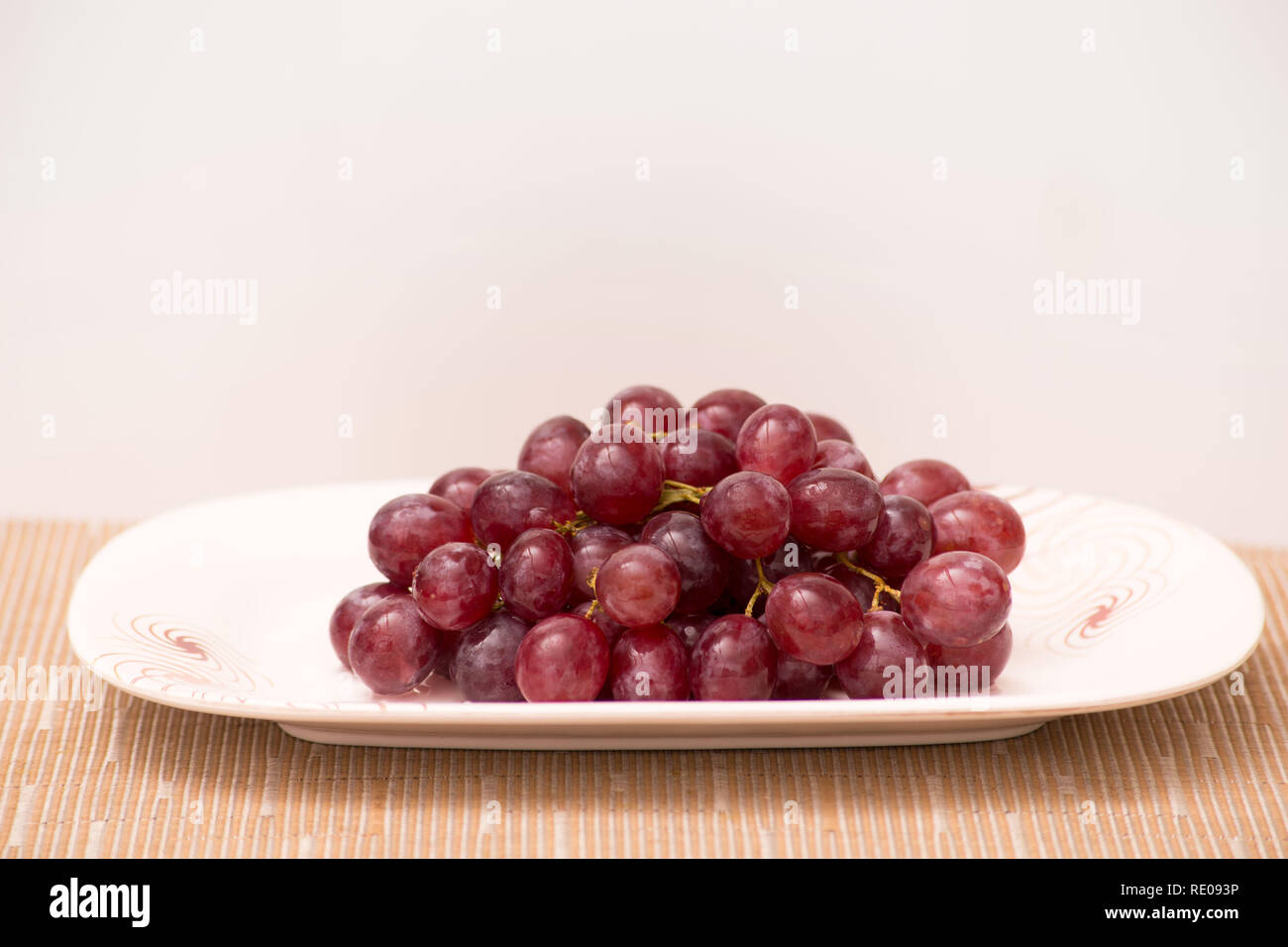 Rote Trauben auf einem Teller und Tisch frisch und nass und süß lecker Stockfoto