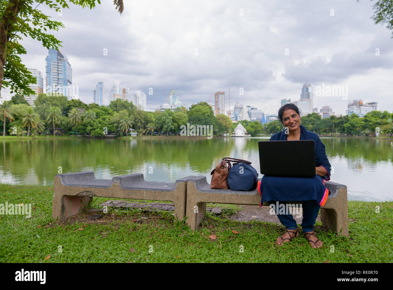 Portrait von Reifen der indischen Frau im Park mit Laptop Stockfoto