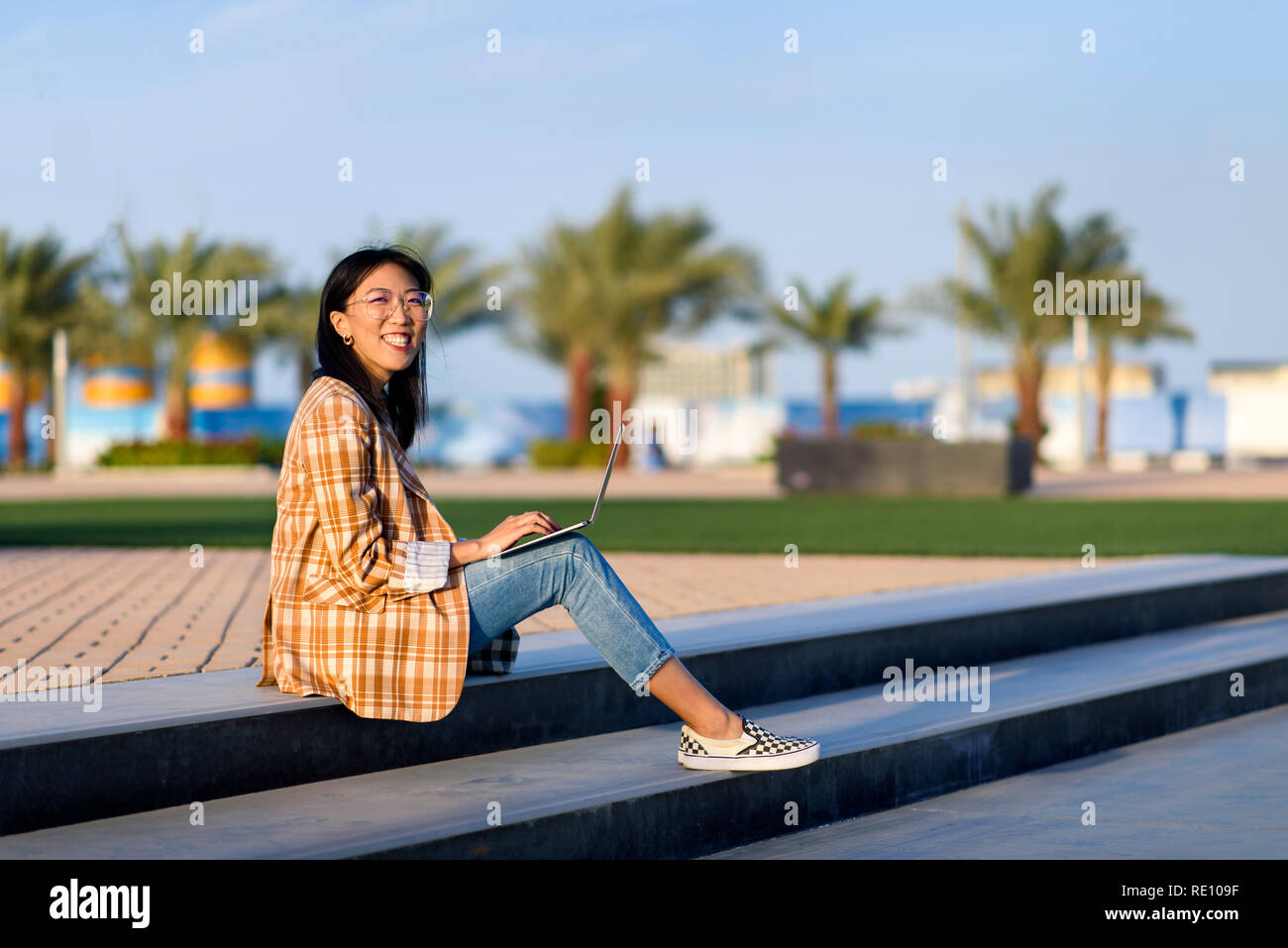 Modische asiatische Mädchen Arbeiten am Laptop im Freien Stockfoto