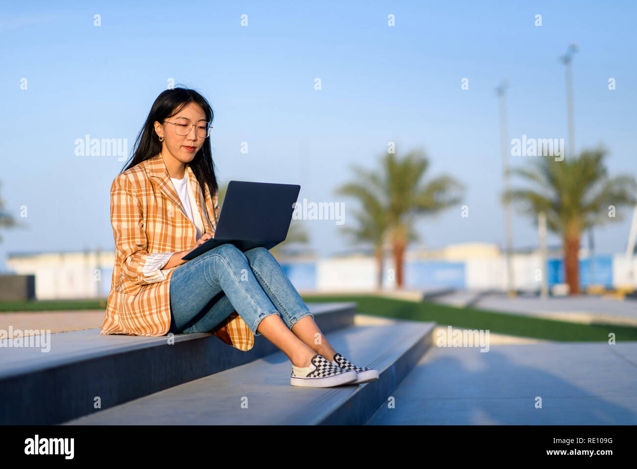 Modische asiatische Mädchen Arbeiten am Laptop im Freien Stockfoto