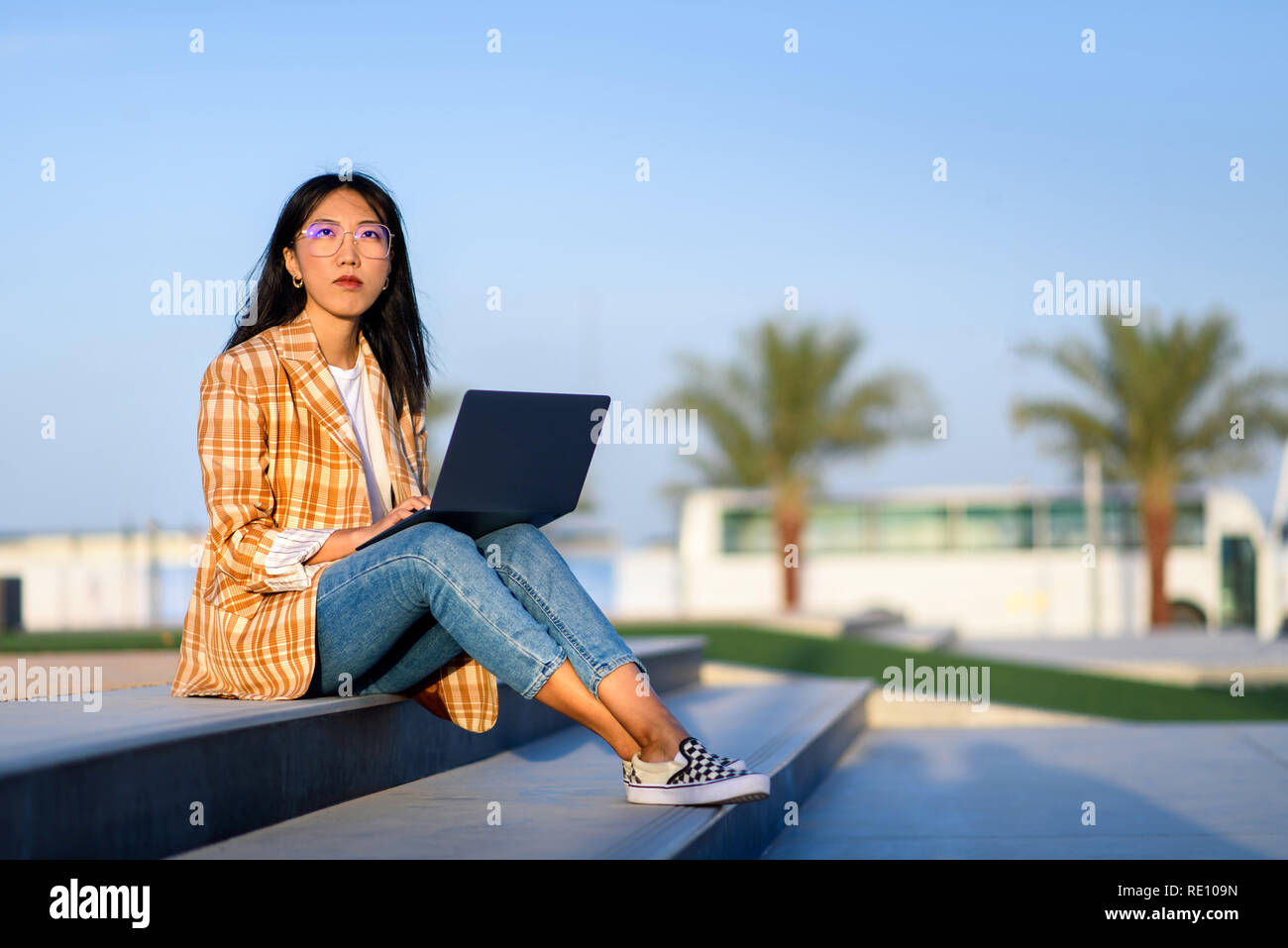 Modische asiatische Mädchen Arbeiten am Laptop im Freien Stockfoto