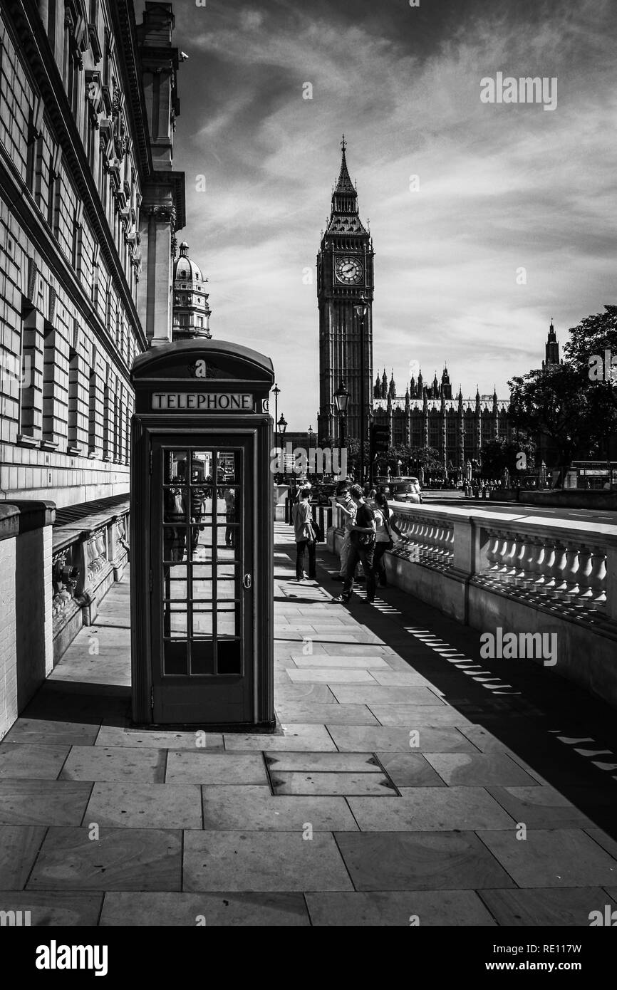 Eine typisch britische Telefonzelle auf dem Bürgersteig mit dem berühmten Elizabeth Tower (Big Ben) im Hintergrund - London, Großbritannien Stockfoto