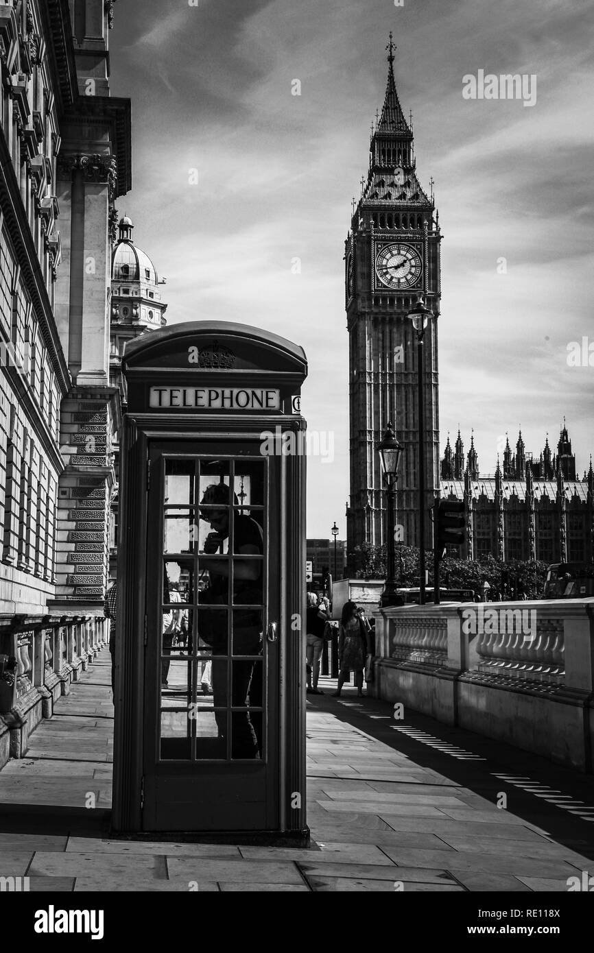 Ein Mann mit dem Telefon in einem typischen britischen Telefonzelle auf dem Bürgersteig mit dem berühmten Elizabeth Tower (Big Ben) im Hintergrund - London, Großbritannien Stockfoto
