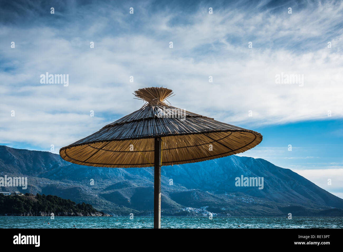 Thatch Sonnenschirm auf Meer und Green Mountain Hintergrund Stockfoto