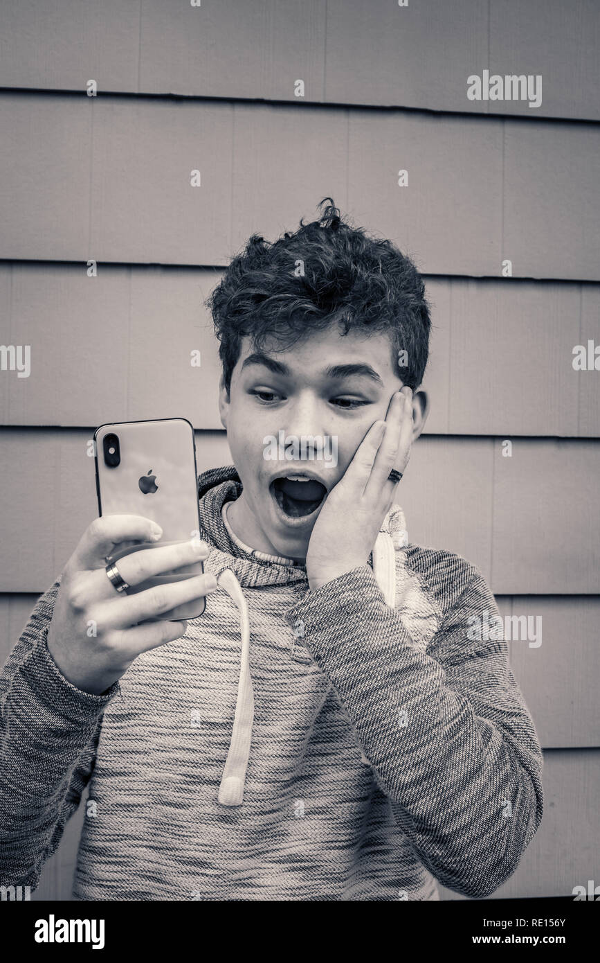 Cute teen Boy, lustige Gesichter während an seinem iPhone X neue Technologie suchen Stockfoto