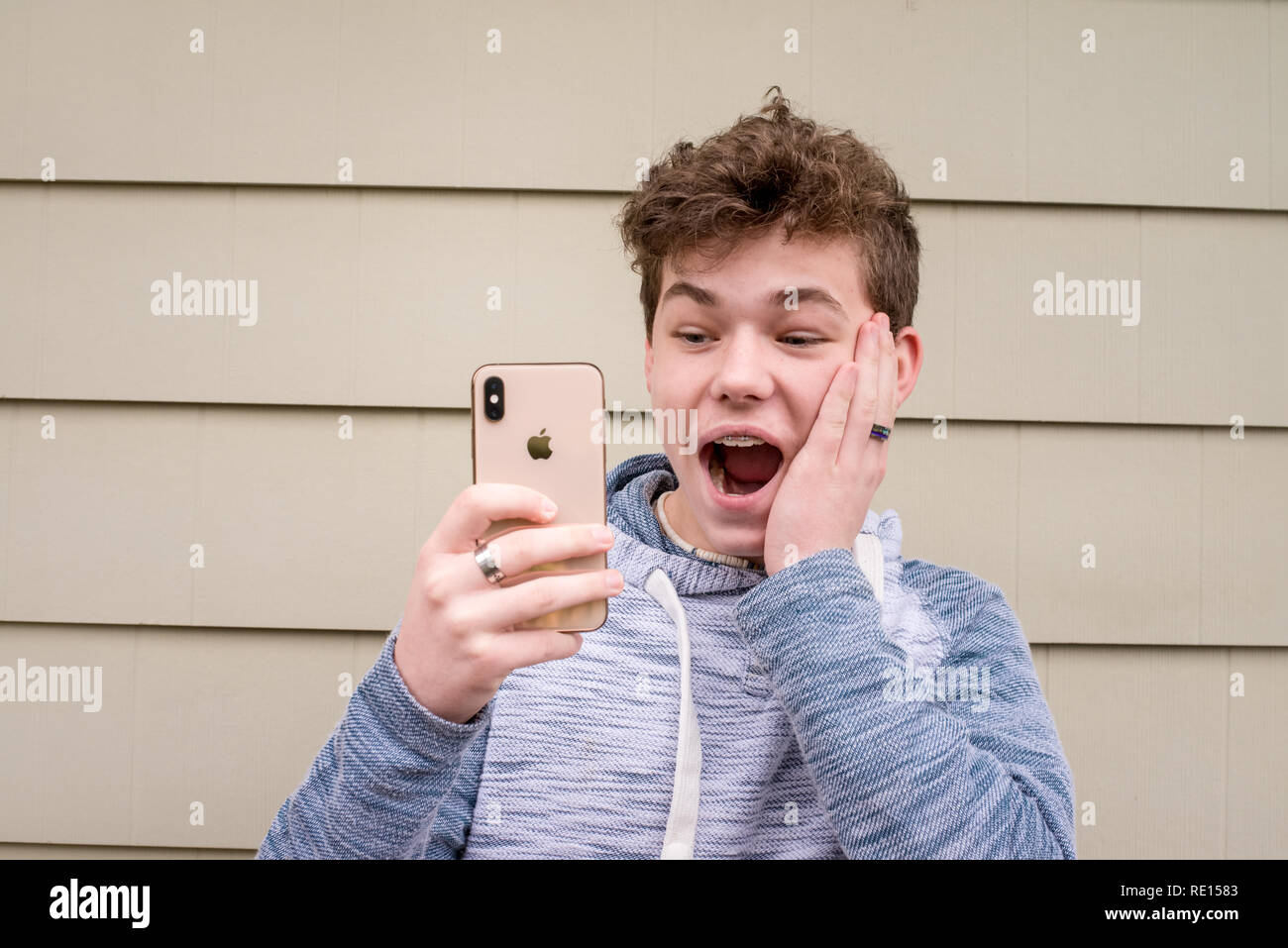 Cute teen Boy, lustige Gesichter während an seinem iPhone X neue Technologie suchen Stockfoto