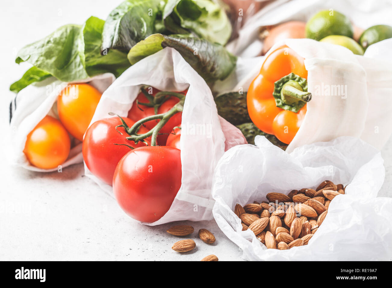 Gemüse in eco Baumwolltaschen, Pfeffer, Tomaten, Kopfsalat, Gurken, Kalk, Zwiebel auf weißem Hintergrund. Null Abfall Lebensmittel einkaufen. Stockfoto