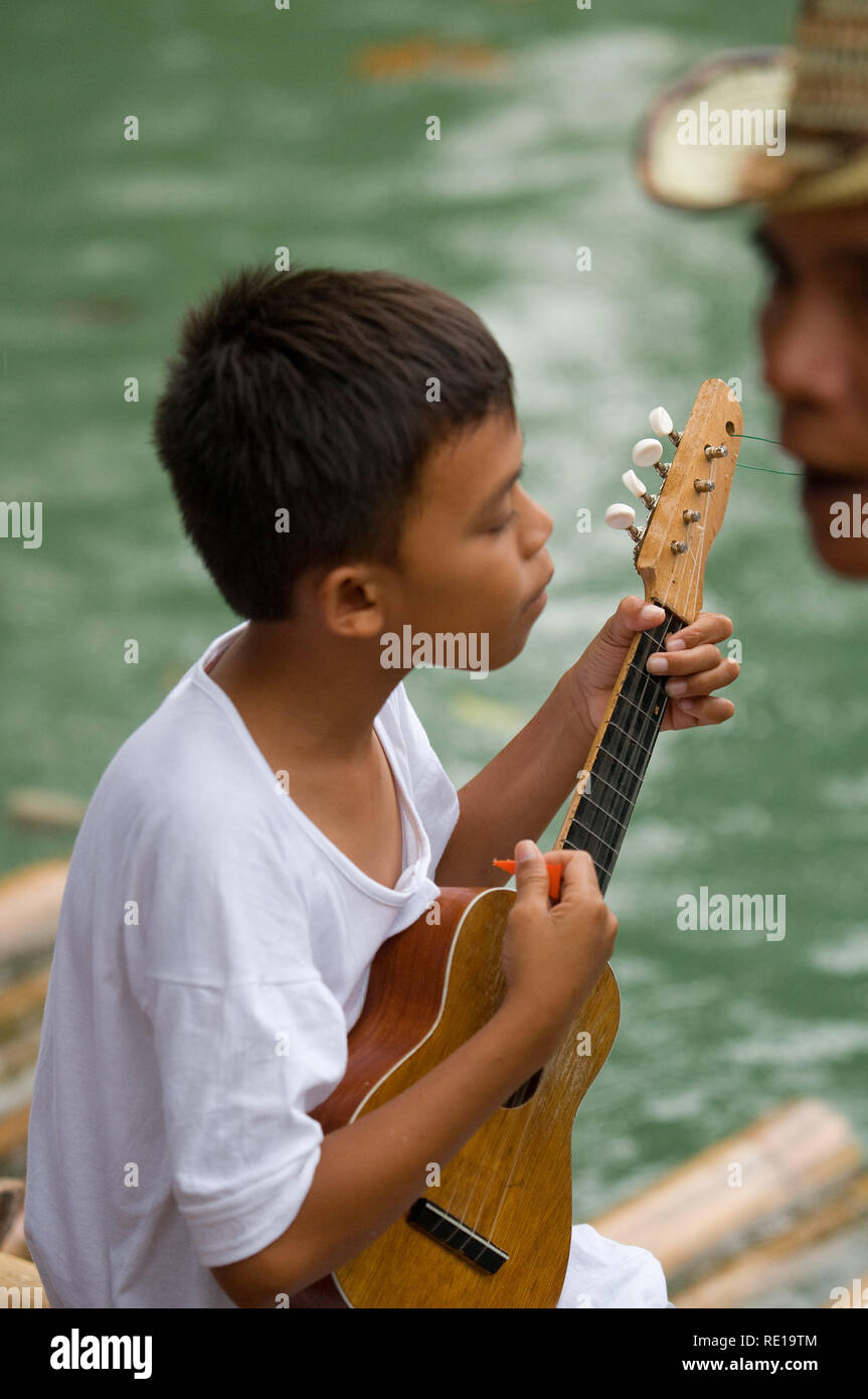 Einige Kinder singen und tanzen am Rande des Loboc River, wenn Touristen kommen, während Sie eine Bootsfahrt unternehmen. Loboc Bohol Philippinen Stockfoto