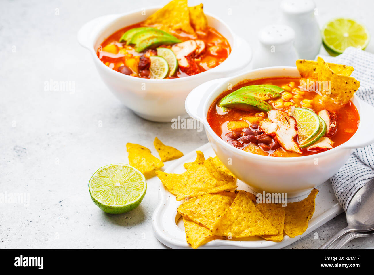 Mexikanische Suppe mit Bohnen, Hühnchen, Mais und Nachos in weißen Schalen. Chili con Carne - traditionelle mexikanische Küche. Stockfoto