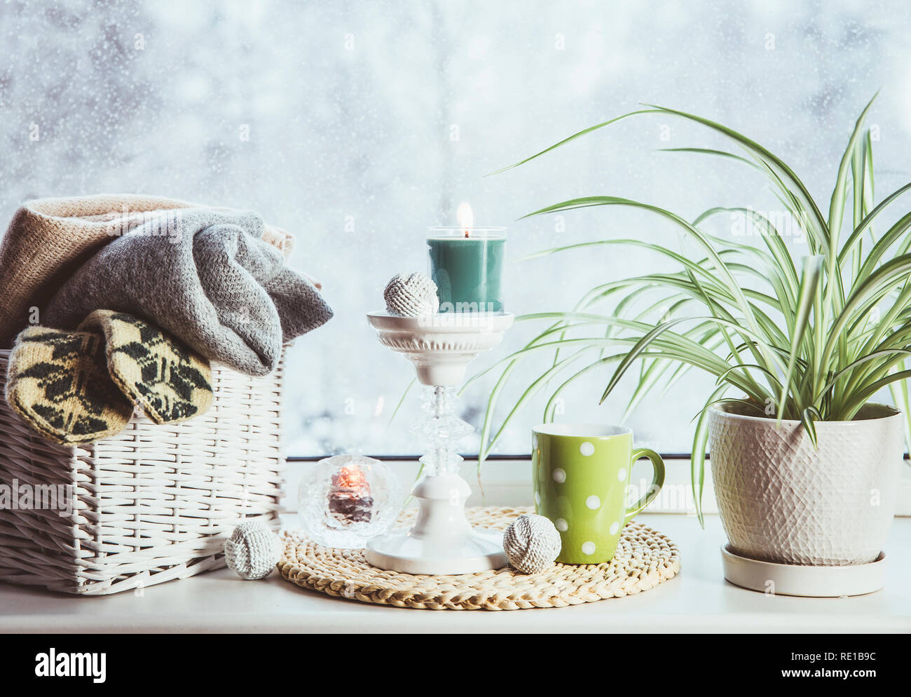Gemütlich im Winter auf der Fensterbank. Im romantischen Stil tall Kerzenhalter, Rattan Korb mit gestrickten Handschuhe und warme Plaids und Decken, Schneefall outdoo Stockfoto Gemütlich im Winter auf der Fensterbank. Im romantischen Stil tall Kerzenhalter, Rattan Korb mit gestrickten Handschuhe und warme Plaids und Decken, Schneefall outdoo Stockfoto