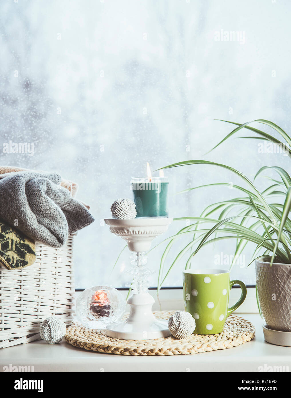 Gemütlich im Winter auf der Fensterbank. Im romantischen Stil tall Kerzenhalter, Rattan Korb mit gestrickten Handschuhe und warme Plaids und Decken, Schneefall outdoo Stockfoto