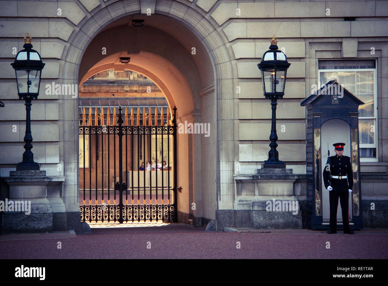 Royal Guard vor einer Sentry box Neben überdimensionalen Laternen und eine reich verzierte Tor am Buckingham Palace in London, Vereinigtes Königreich Stockfoto