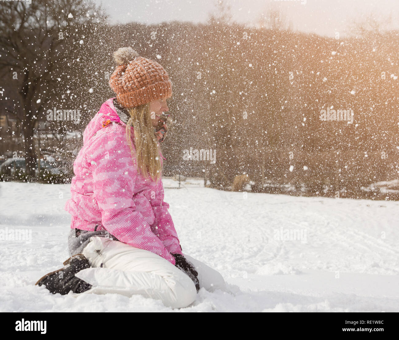 Fröhliche junge Frau spielt mit Schnee im Winter Stockfoto