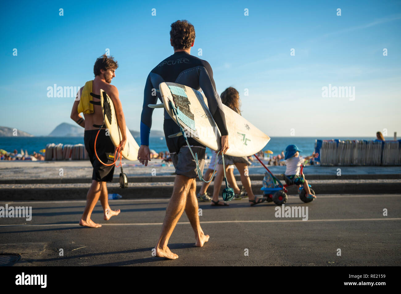 RIO DE JANEIRO - MÄRZ 24, 2017: Ein paar barfüßige junge Surfer Spaziergang auf der Straße mit Surfbrettern auf den Ipanema Beach Boardwalk. Stockfoto