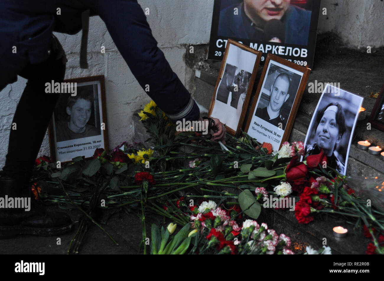 Moskau, Russland. Jan, 2019 19. Eine Frau ist mit zwei Zigaretten durch das Bildnis der Erschlagenen Antifaschist Ivan Khutorskoy. Die Menschen sind mit Blumen an der Stelle, wo Stanislaw Markelow und Anastasia Baburova ermordet wurden. Hunderte in Moskau versammelt, um den 10. Jahrestag ihres Todes in den Händen eines neo-Nazi am 19. Januar 2009 zu gedenken. Credit: Aleks Lokhmutov/Alamy Leben Nachrichten. Stockfoto