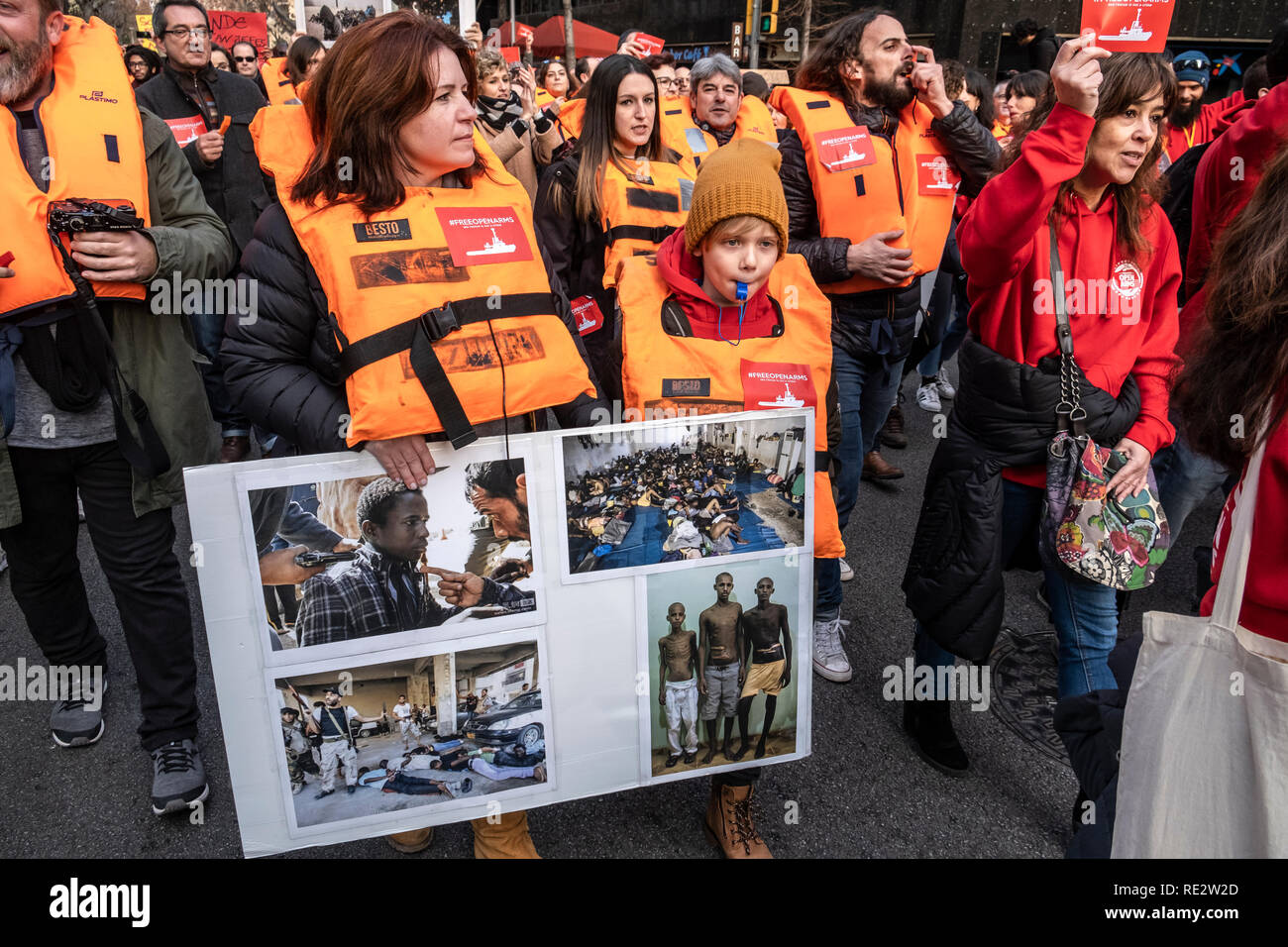 Barcelona, Spanien. 19. Jan 2019. Die Demonstranten werden gesehen, Schwimmwesten und halten ein Banner mit Bildern von Gewalt in Libyen während des Protestes. Die offenen Arme das Schiff sich in den Hafen von Barcelona seit dem vergangenen 7. Januar statt. Verschiedene soziale Organisationen zusammen mit NGO Freiwillige vor der Regierung Delegation Spaniens demonstrieren, für die sofortige Freilassung des Schiffes zu verlangen, so dass er in die Rettung von Menschen im Mittelmeer operieren können. Credit: SOPA Images Limited/Alamy leben Nachrichten Stockfoto