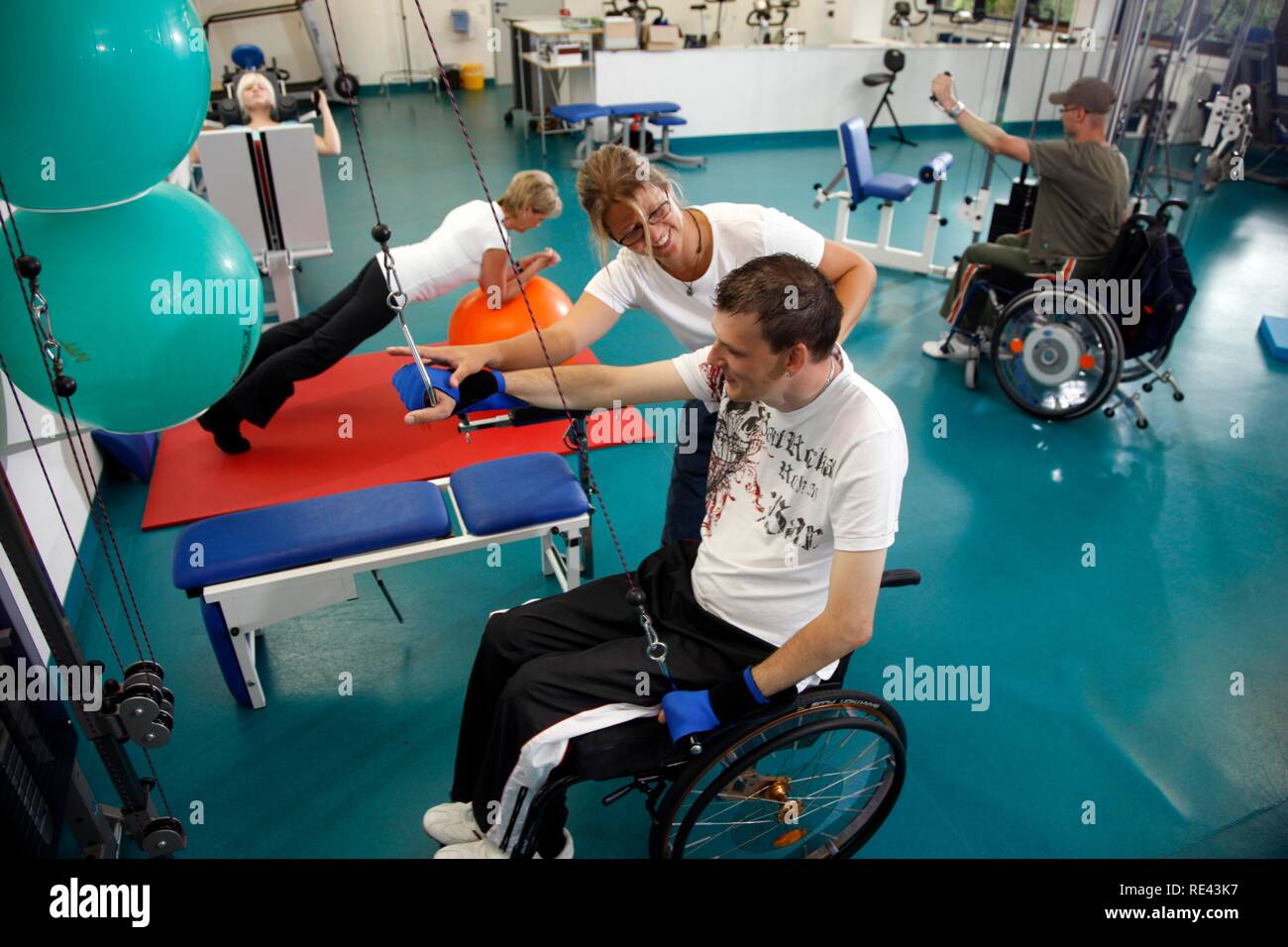 Patienten, die in den Muskeln Training auf verschiedenen Maschinen in einer Turnhalle, Physiotherapie, Physikalische Therapie in einer neurologischen Stockfoto