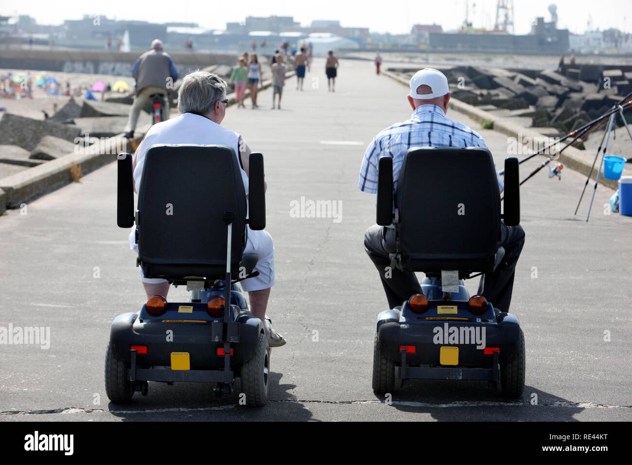 Senioren auf motorisierte Rollstühle auf einer konkreten Wellenbrecher am Strand von Scheveningen, Strand Stadtteil von Den Haag, Stockfoto