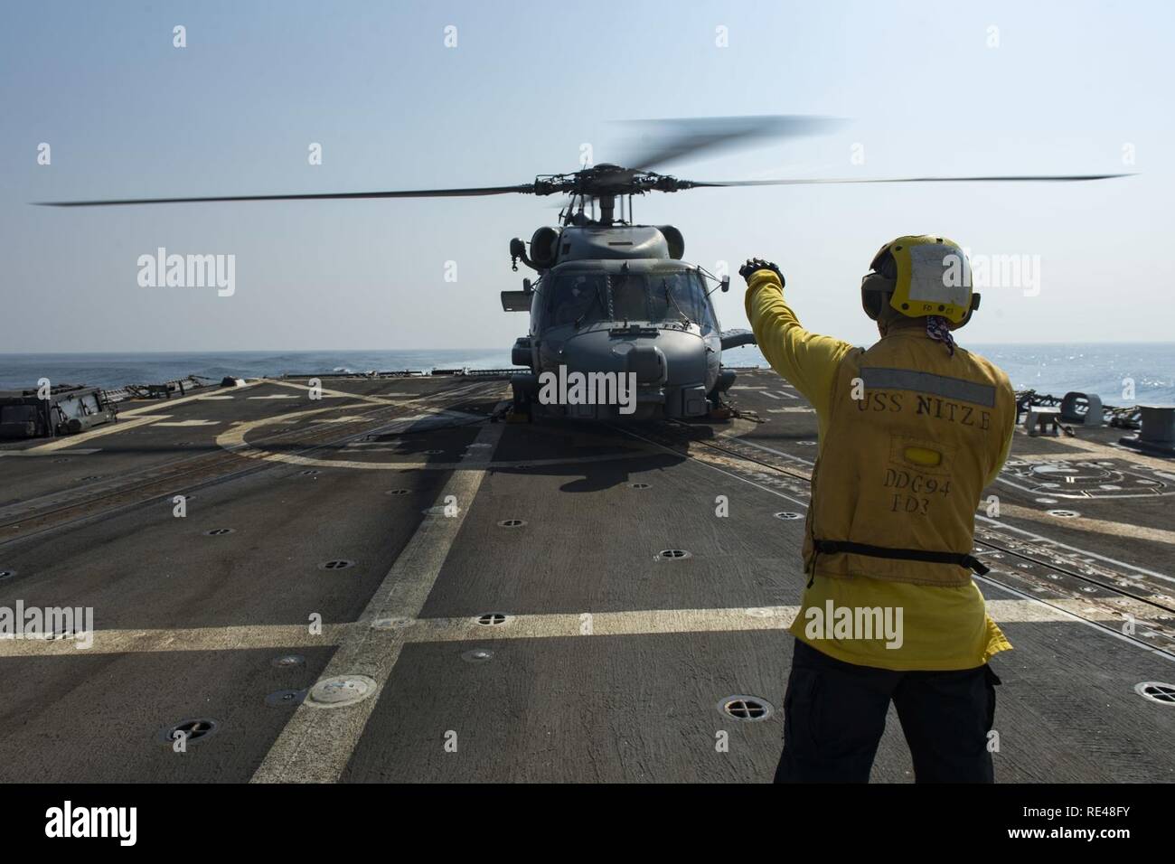 ARABIAN GULF (Nov. 16, 2016) Petty Officer 2nd class Kaleb, Metz, der Geführten zugeordnet Anti-raketen-Zerstörer USS Nitze (DDG94), leitet eine MH-60R Sea Hawk Hubschrauber zum Sumpf Füchse von Hubschrauber Maritime Strike Squadron (HSM) 74 zugeordnet. Metz serviert an Bord Nitze als bootsmann Mate und ist verantwortlich für die Erhaltung, Pflege und deck Entwicklungen. Nitze, eingesetzt als Teil der Eisenhower Carrier Strike Group, unterstützt Maritime Security Operations und Theater Sicherheit Zusammenarbeit in den USA 5 Flotte Bereich der Operationen. Stockfoto