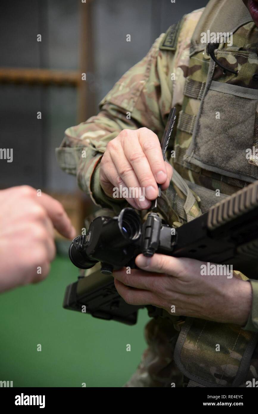 Mitglied der Britischen Streitkräfte, die zu den lokalen Einheiten zugeordnet, passt die Augen seine Waffe", die im Rahmen der L 85 A2 rifle Kalibrierung bei der Schulung Support Center Benelux 25 m Reichweite im Innenbereich, in Chièvres Air Base, Belgien, November 30, 2016. Die britischen Truppen unter Aufsicht der britischen Joint European Training Team geschult Stockfoto