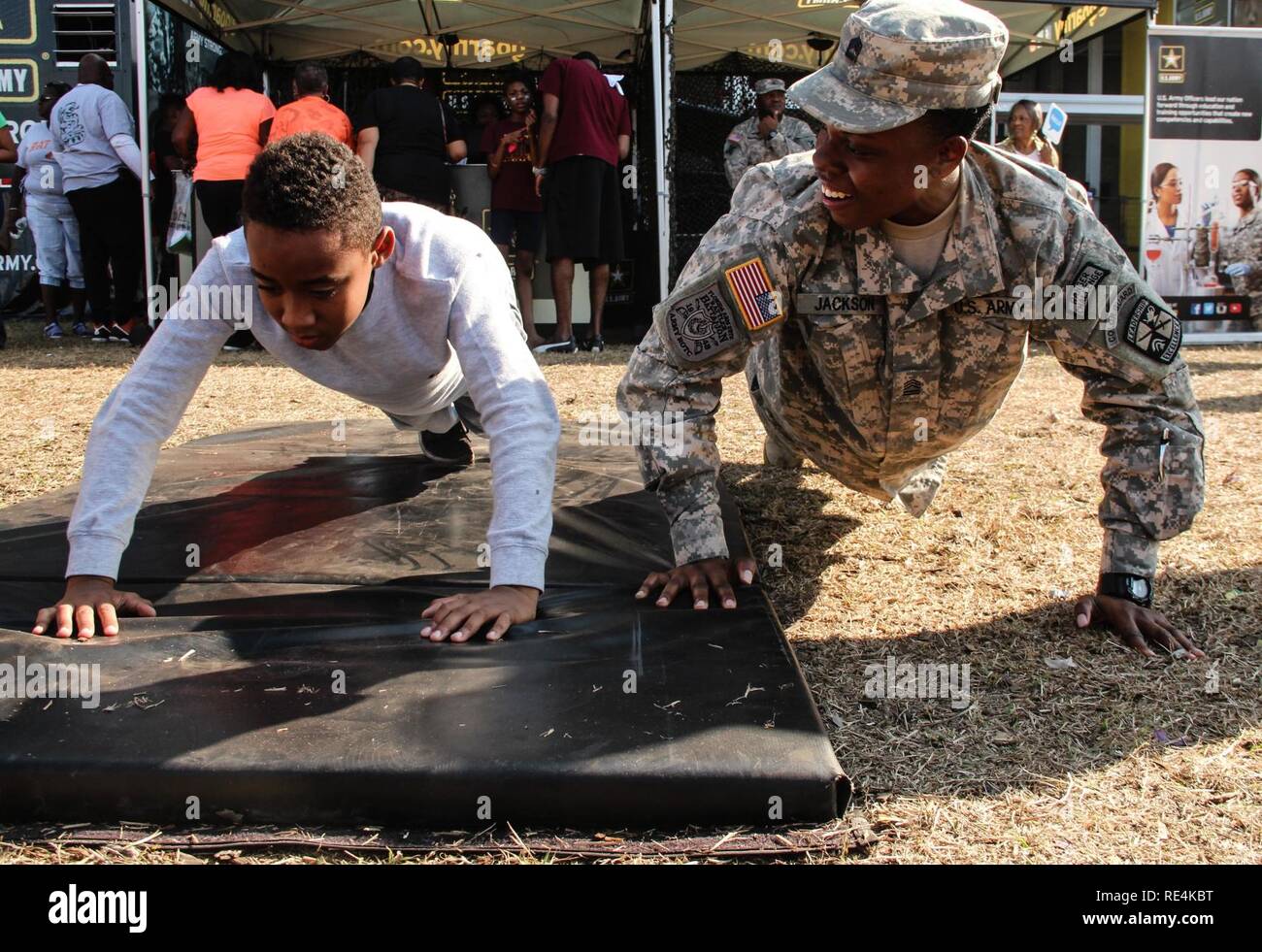 Ein Florida A&M University Army Reserve Officer Training Corps Cadet motiviert ein junger Mann während eines pushup Herausforderung durchgeführt 19.11.2016, an der GoArmy.com interaktive Stand auf dem Messegelände ausserhalb des Lagers Welt Stadion in Orlando, Fla. Mehrere FAMU Armee ROTC Kadetten gelegen Active Duty beigetreten und Reservisten bei der Förderung zehntausende Fans an der Florida Klassiker - eine der größten Fußball-rivalitäten der Nation zwischen zwei historisch schwarze Hochschulen - ihre Kraft, Ausdauer und geistige Eignung in verschiedenen interaktiven Aktivitäten zu prüfen. Die Veranstaltung bot auch einzigartige opp Stockfoto