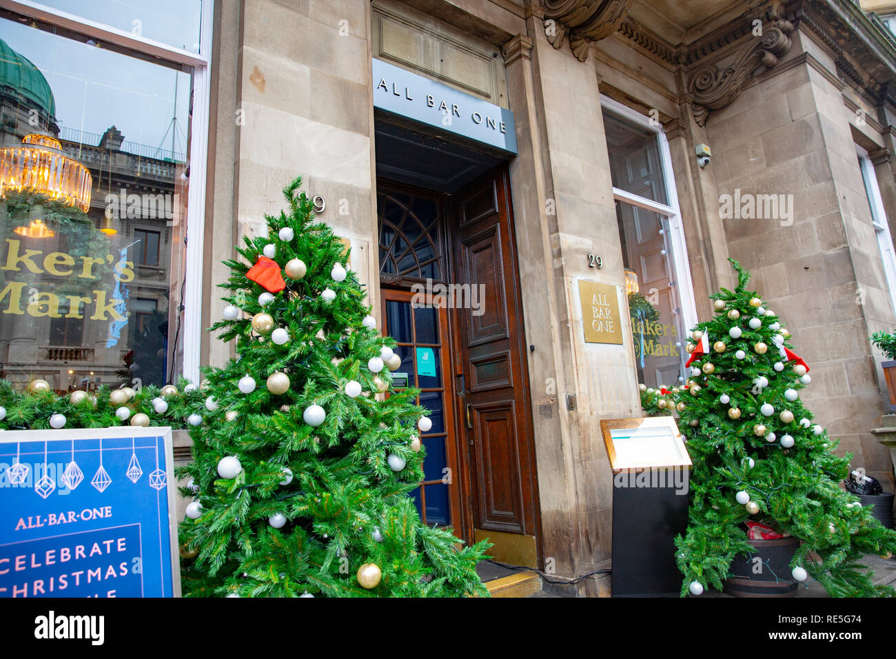 Weihnachtsbäume vor dem Eingang zu einem All Bar One Pub in Edinburgh, Schottland, Großbritannien Stockfoto