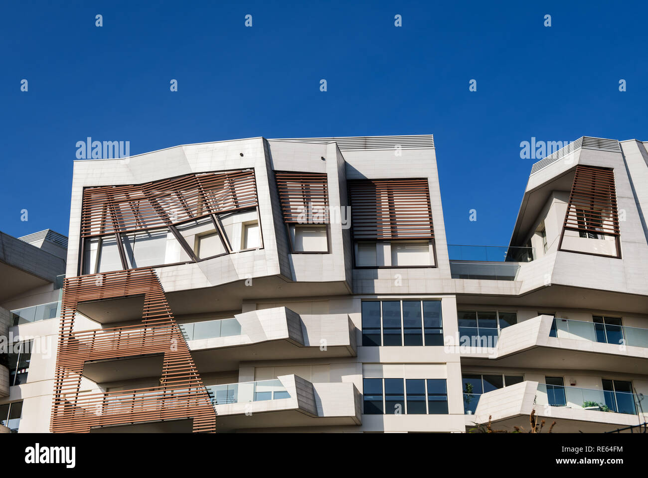 Ungewöhnliche modernes Appartementhaus mit eckigem Design und Holz Holz Verschalungen Detail auf die Mauer große Balkone vor blauem Himmel Stockfoto