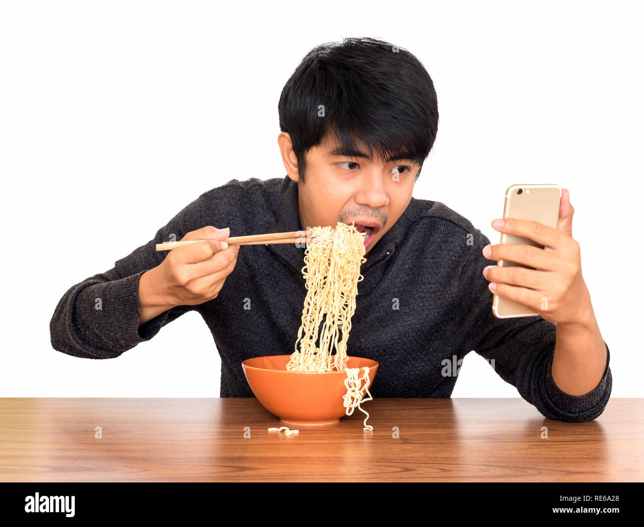 Mann essen chinesische Nudelsuppe monströs während der Suche und Verwendung von Smartphone isolieren auf weißem Hintergrund mit Freistellungspfaden. Konzept der Smartphone addict Stockfoto