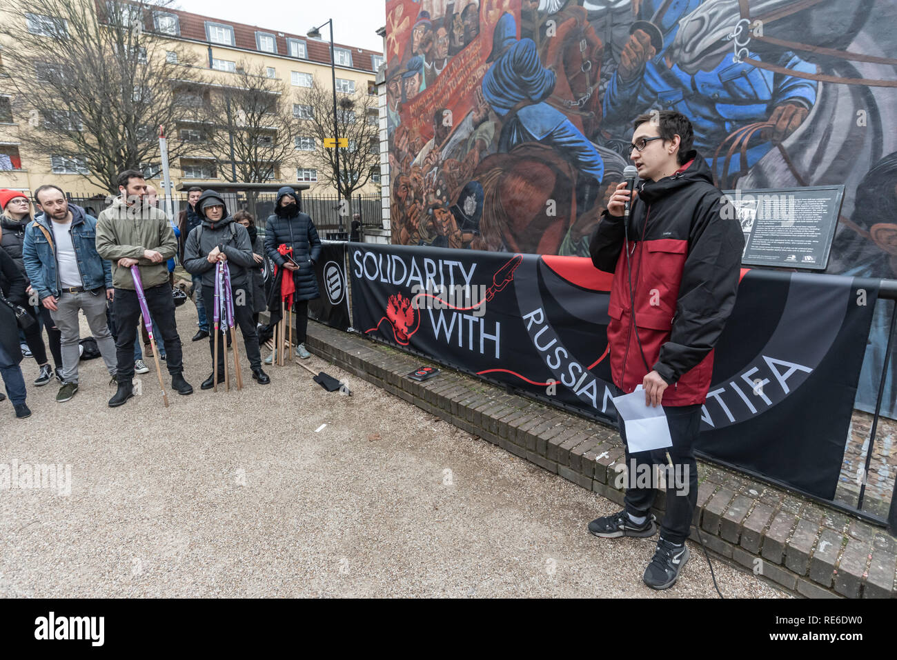 London, Großbritannien. 19. Januar 2019. Eine russische Genosse spricht auf der Kundgebung von Anarchisten und Antifaschisten am Kabel St Wandbild Rassismus, Fremdenfeindlichkeit, Faschismus und der Aufschwung der rechtsextremen Populismus zu erheben und ihre Solidarität mit der russischen Antifaschisten, die festgenommen wurden, gerahmt und in einer brutalen Welle der Repression gefoltert. Gefängnis für fünf bis zwanzig Jahre zu zeigen. Die Kundgebung fand am Jahrestag der brutalen Ermordung von Faschisten auf der Straße von zwei russischen Antifaschisten in 2009. Af: Peter Marschall/Alamy leben Nachrichten Stockfoto