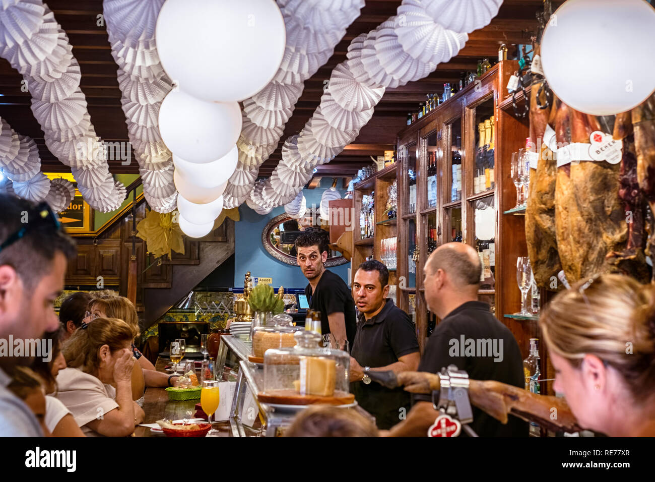 Malaga, Spanien - 12. August 2018. Die Menschen trinken und essen an traditionellen Tapas Bar mit Trocken-Schinken Beine und vintage Einrichtung in Malaga, Spanien Stockfoto