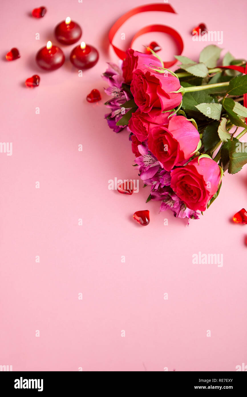 Gemischte Blumen Blumenstrauß mit Rosen, Kerzen und herzförmige Acryl  Dekorationen auf rosa Hintergrund. Geschenk zum Valentinstag, 8. März oder  romantisches Date Stockfotografie - Alamy