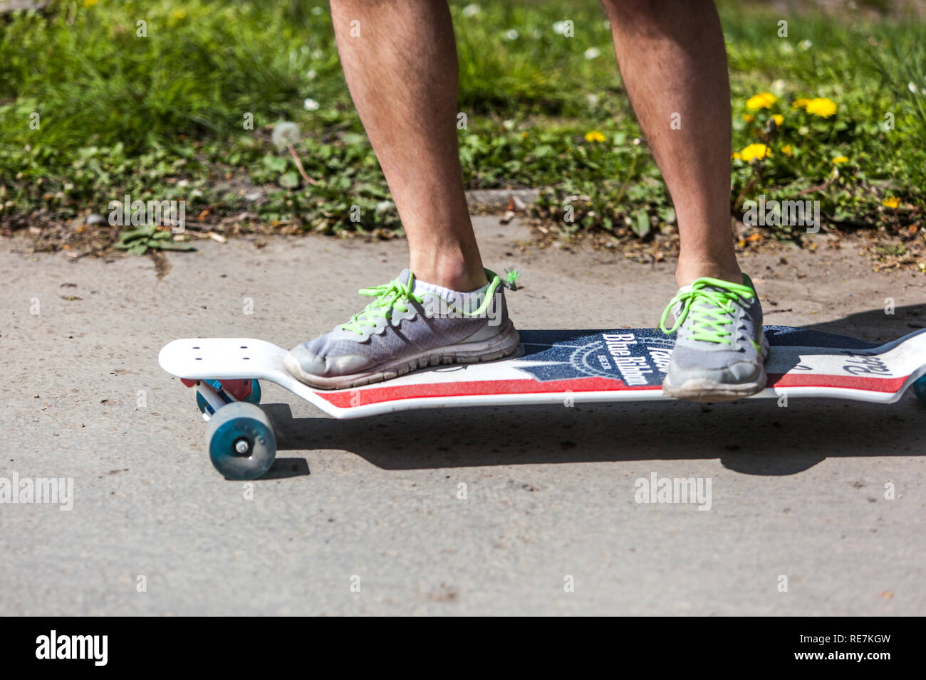 Männliche Beine in Sneakers auf Skateboard Natur Stockfoto