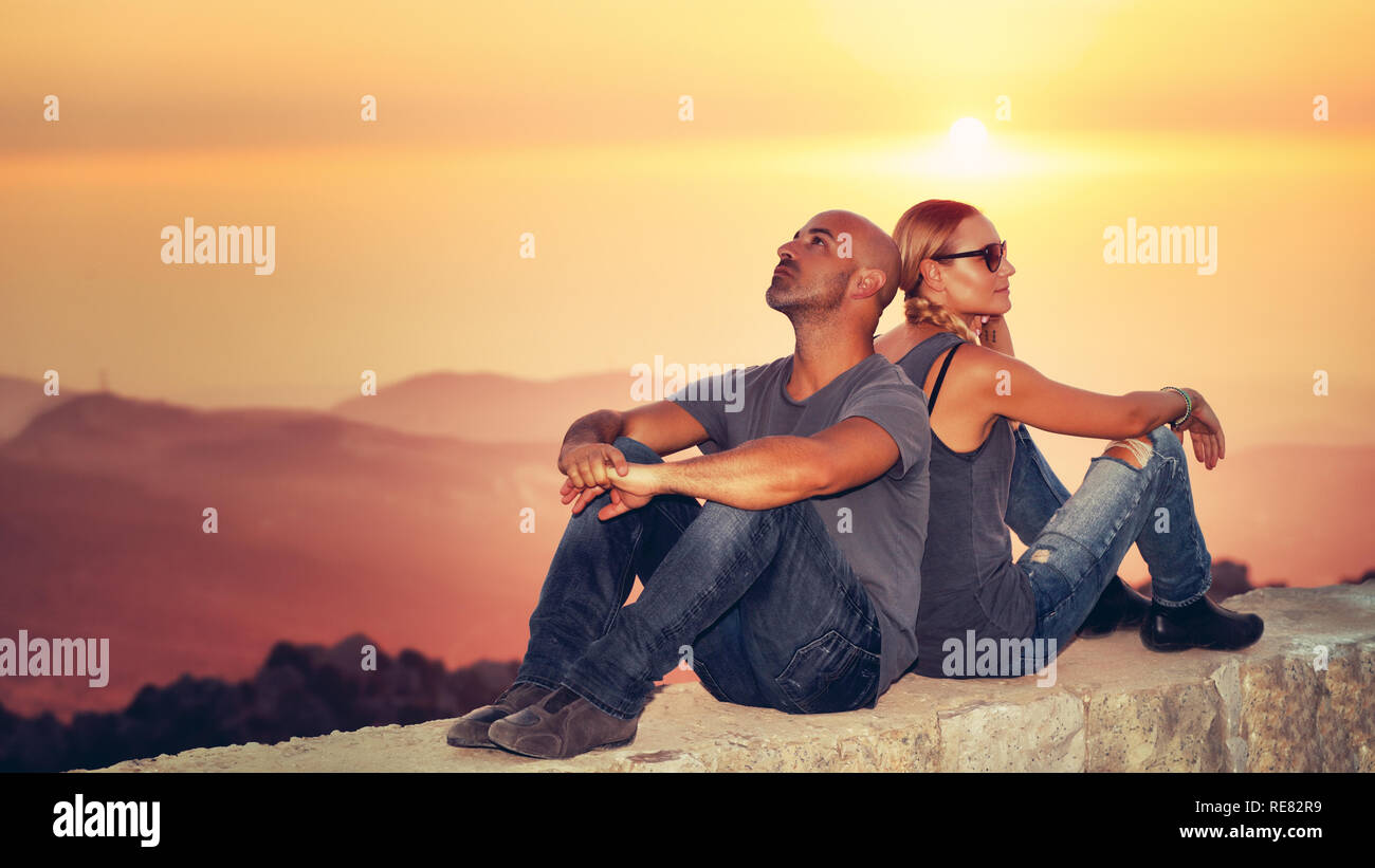 Glückliches Paar genießen Blick auf den Sonnenuntergang, hübscher Kerl mit Freundin zurück sitzen miteinander über Berge Hintergrund in mildem orange Licht zu rücken, Rom Stockfoto